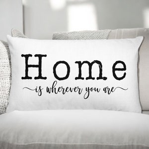 May include: A white ceramic mug with a black handle and the text "But First, Coffee" in a bold, black font. The mug is set against a neutral background, highlighting its simple design.