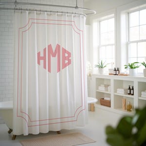 May include: White shower curtain with a pink monogram of the letters "HMB" in a decorative frame.