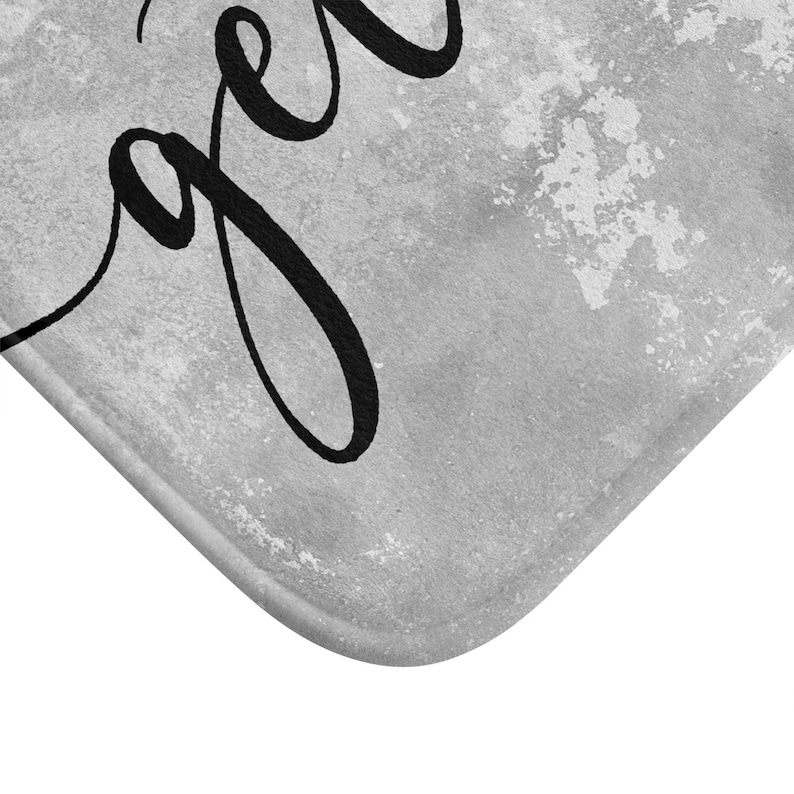 May include: A gray and white bath mat with the word "together" in black script. The mat has a textured, watercolor-like background. The corner of the mat is visible, showing a rounded edge.