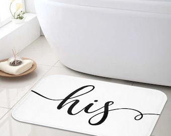 May include: White bath mat with the word "his" written in black cursive script.
