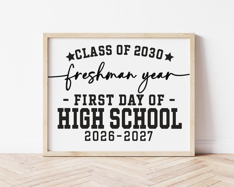 May include: A framed print with the text "CLASS OF 2030 freshman year - FIRST DAY OF - HIGH SCHOOL 2026-2027" in black lettering. The frame is a light wood colour, and the background is white.