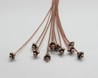 May include: A bunch of copper colored head pins with a flower shaped head. The head pins are about 1 inch long.
