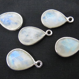 May include: Five pearlescent white teardrop-shaped moonstone pendants with silver bail settings.