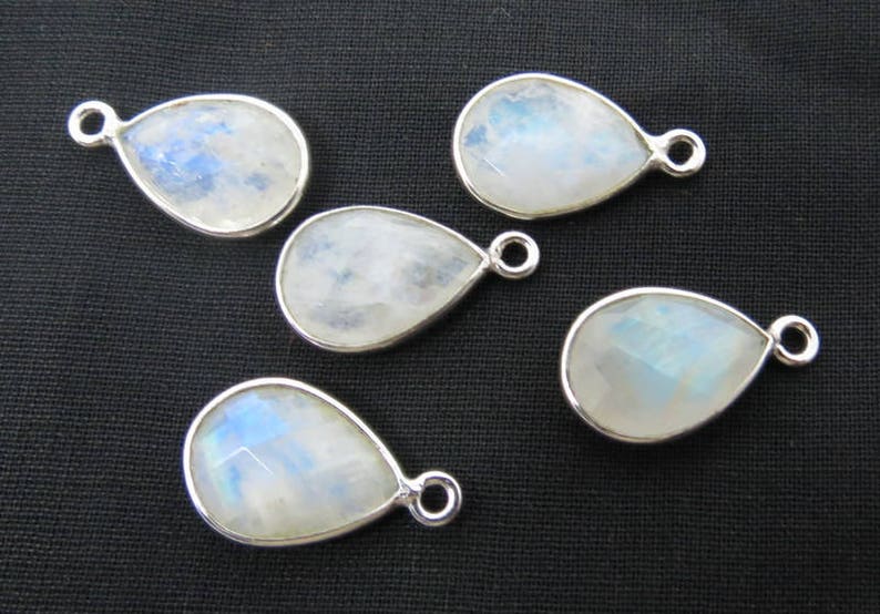 May include: Five pearlescent white teardrop-shaped moonstone pendants with silver bail settings.