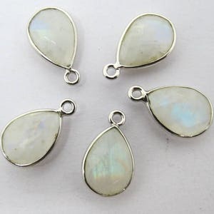 May include: Five silver teardrop-shaped pendants with white moonstone gemstones. Each pendant has a small loop at the top for attaching to jewelry.