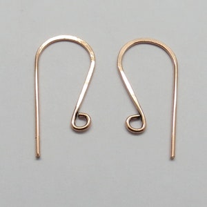 May include: A pair of rose gold earring hooks. The hooks are made of metal and have a simple, elegant design.