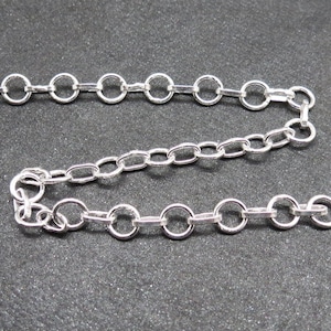 Op de afbeelding: Een zilveren ketting met een delicaat, ovaalvormig schakellinkontwerp. De ketting is ongeveer 45 cm lang.