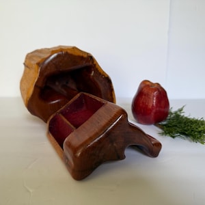 May include: A handcrafted wooden box with a lid and a compartmented interior. The box is a rich brown color with a natural wood grain finish. A red apple and a sprig of greenery are next to the box.