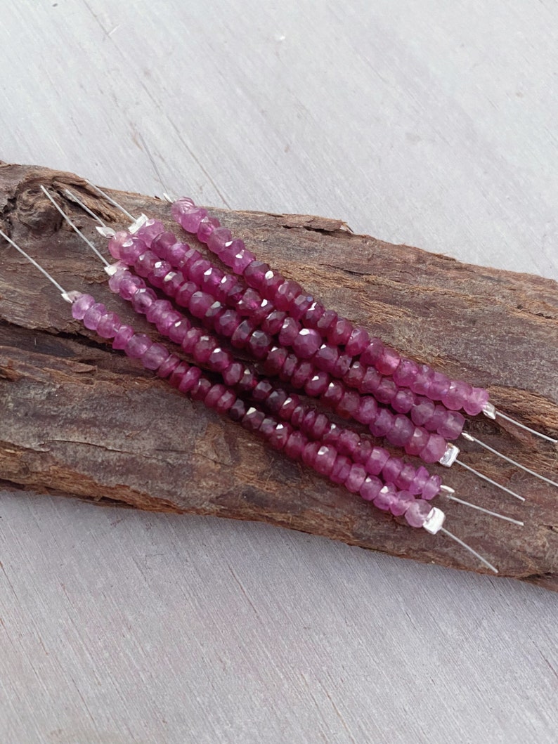 May include: Multiple strands of pink ruby beads on silver wire. The beads are faceted and have a slightly irregular shape.