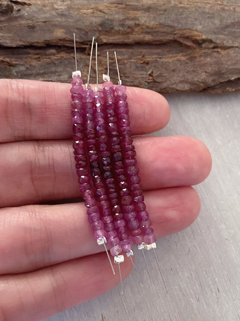 May include: Five strands of pink gemstone beads on silver wire. The beads are faceted and have a square shape.