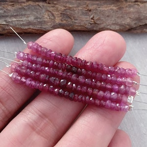 May include: A strand of pink ruby beads, faceted and strung on wire. The beads are small and uniform in size, and the strand is approximately 16 inches long.
