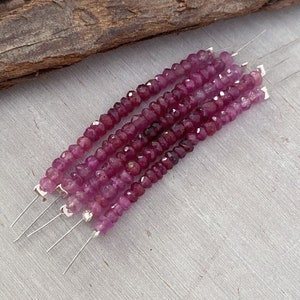 May include: A strand of pink gemstone beads on a silver wire. The beads are faceted and have a slightly irregular shape.