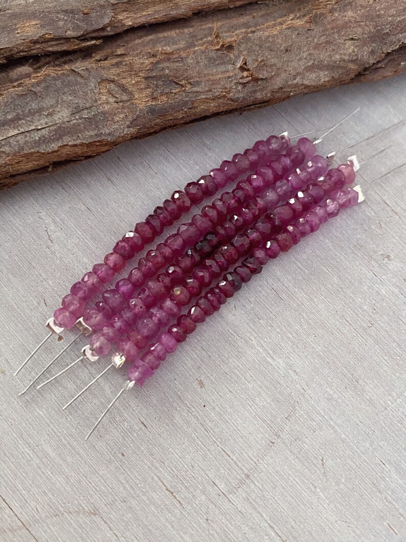 May include: A strand of pink gemstone beads on a silver wire. The beads are faceted and have a slightly irregular shape.