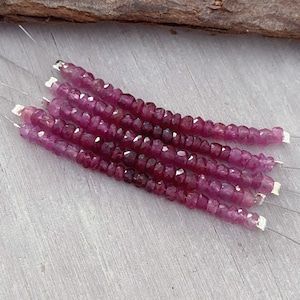 May include: A strand of pink ruby beads, approximately 4mm in size, strung on silver wire. The beads are faceted and have a slightly irregular shape.
