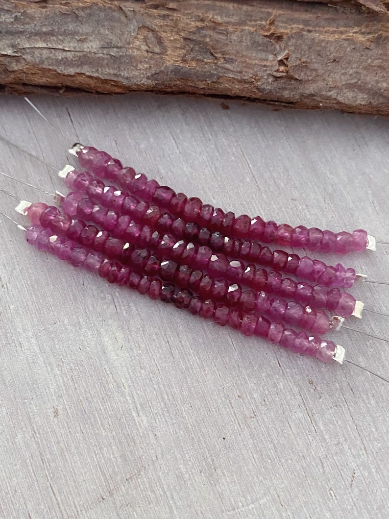 May include: A strand of pink ruby beads, approximately 4mm in size, strung on silver wire. The beads are faceted and have a slightly irregular shape.