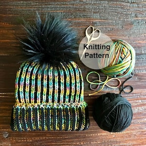 May include: A black and green striped knit hat with a black faux fur pom pom. The hat is lying on a wooden surface with two balls of yarn and a pair of scissors. The text "Knitting Pattern" is written on a white circle.