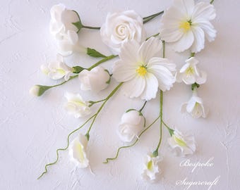 Könnte beinhalten: Eine Sammlung weißer Zuckerblumen, darunter Rosen, Kosmeen und Freesien, auf weißem Hintergrund arrangiert. Die Blumen sind aus Fondant und eignen sich perfekt zum Dekorieren von Torten und Cupcakes.  Bespoke Sugarcraft.