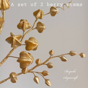 A set of two gold berry stems with star-shaped berries. The stems are made of wire and the berries are made of sugar paste. The stems are perfect for adding a touch of elegance to your cakes and cupcakes.