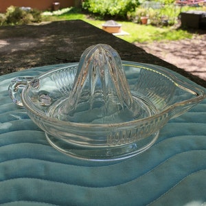 Peut inclure: Un presse-agrumes en verre transparent avec un motif strié et un bec verseur. Le presse-agrumes a une poignée sur le côté et un cône central avec des stries.