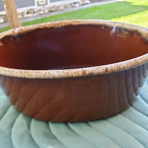 Peut inclure: Un plat à four ovale en céramique émaillée marron et blanche. Le plat a un bord blanc et un intérieur marron.