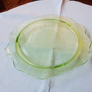 May include: A green glass serving plate with a scalloped edge and an etched floral design.
