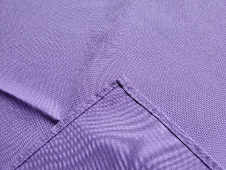 May include: A close-up of a lavender fabric with a visible seam. The fabric has a smooth texture and a slight sheen. The seam is stitched with a matching thread, creating a clean, finished edge.