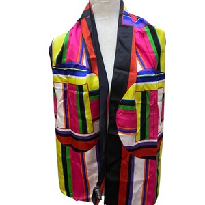 Peut inclure: Écharpe en soie colorée avec un motif géométrique. L'écharpe présente un mélange de couleurs vives, notamment du jaune, du rose, du vert et du noir. L'écharpe est drapée sur une tête de mannequin blanche.