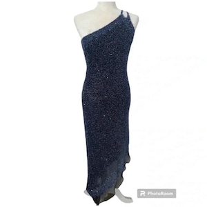 May include: A one-shoulder, navy blue, sequined evening gown with a high slit and a flowing skirt.