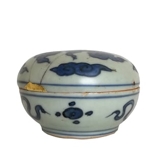 Peut inclure: Une petite boîte ronde en céramique bleue et blanche avec un couvercle. La boîte est décorée d'un motif de nuage et présente une fissure sur le couvercle.