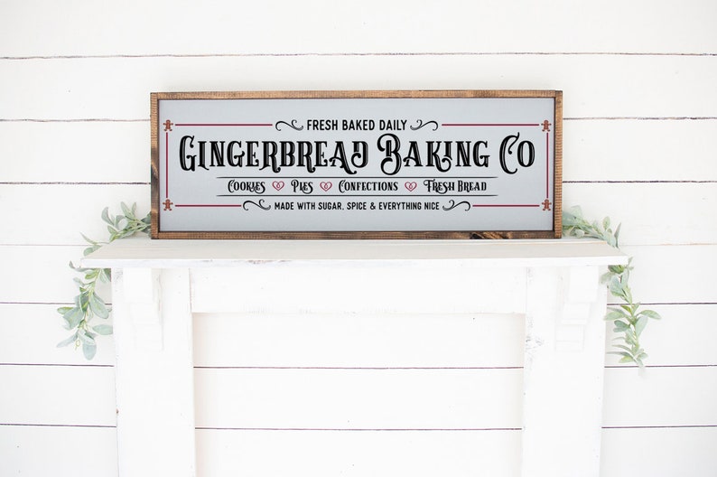 Pu&ograve; includere: Un cartello rettangolare con cornice in legno e sfondo grigio chiaro che presenta il testo nero GINGERBREAD BAKING CO, FRESH BAKED DAILY, COOKIES, PIES, CONFECTIONS, FRESH BREAD e MADE WITH SUGAR, SPICE & EVERYTHING NICE.