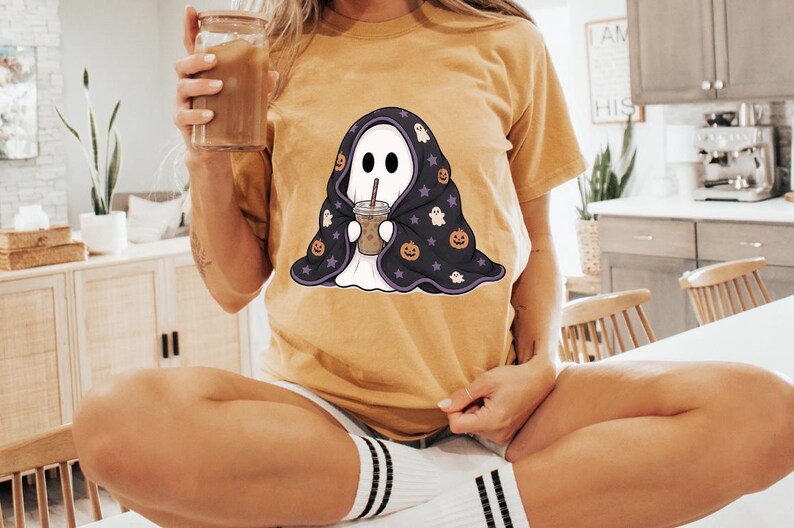 Halloween ghost PNG clipart with a cute ghost wrapped in a patterned blanket and holding a cold coffee cup with a striped straw.