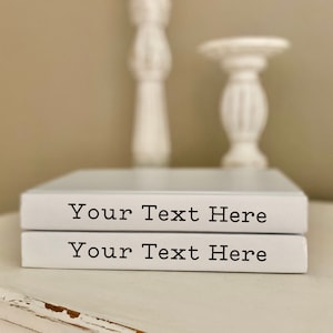 May include: Two white decorative books with the text "Your Text Here" on the front of each book. The books are stacked on top of each other.