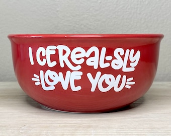 May include: Red ceramic bowl with white lettering that says "I cereal-sly love you".