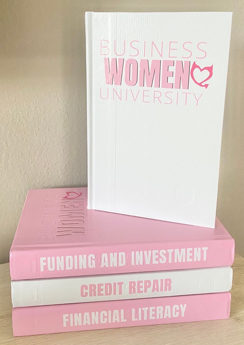 May include: A stack of books with the title "BUSINESS WOMEN UNIVERSITY" in pink lettering. The top book is white, and the others are pink. The titles "FUNDING AND INVESTMENT", "CREDIT REPAIR", and "FINANCIAL LITERACY" are visible.