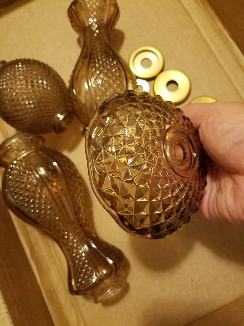 May include: Several vintage amber glass perfume bottles and atomizer tops. The bottles have a diamond pattern and a bulbous shape. The atomizer tops are gold-colored. The bottles are in a cardboard box.