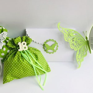 Puede incluir: Bolsas de regalo de lunares verdes y blancos con adornos de mariposa blanca y cinta verde. Tambi&eacute;n se incluye una tarjeta blanca con un recorte de mariposa verde y el texto "5 MAGGIO 2019 -  Battesimo di Viola".