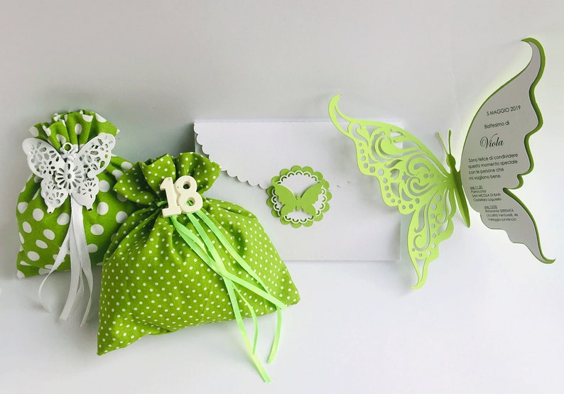 Puede incluir: Bolsas de regalo de lunares verdes y blancos con adornos de mariposa blanca y cinta verde. Tambi&eacute;n se incluye una tarjeta blanca con un recorte de mariposa verde y el texto "5 MAGGIO 2019 -  Battesimo di Viola".