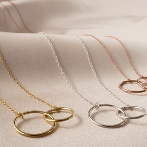 May include: Three gold necklaces with interlocking circle pendants. The necklaces are in gold, silver, and rose gold.