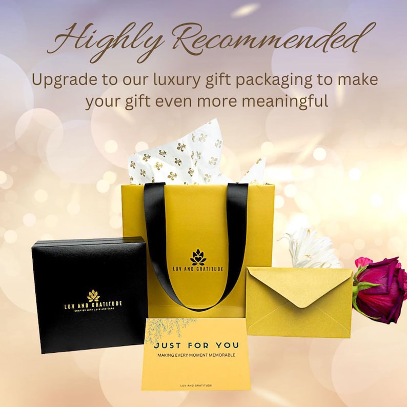 May include: A yellow gift bag with black handles and a black box with the text "LUV AND GRATITUDE" printed on it. The bag has a white tissue paper lining and the text "LUV AND GRATITUDE" printed on the front. A yellow envelope and a card with the text "JUST FOR YOU MAKING EVERY MOMENT MEMORABLE" are also visible.