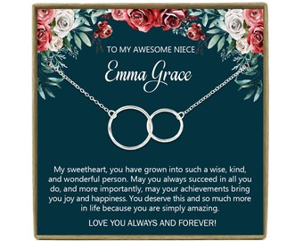 May include: A silver necklace with two interlocking circles, presented on a teal background with floral accents. The text reads "TO MY AWESOME NIECE Emma Grace" and a heartfelt message. The necklace is a thoughtful gift.