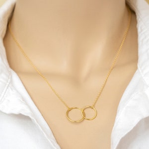 May include: A gold chain necklace with two interlocking circles as a pendant.