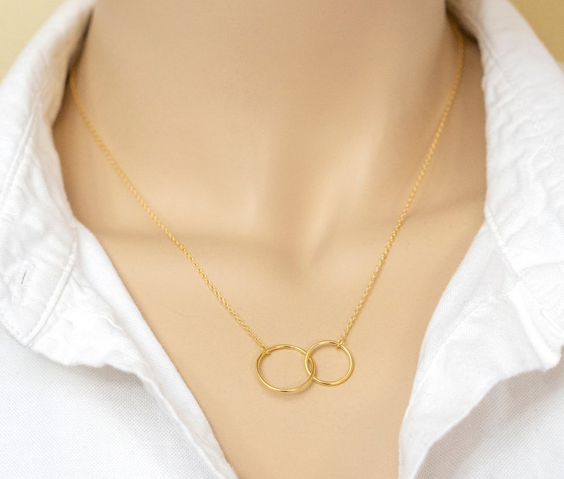 May include: A gold chain necklace with two interlocking circles as a pendant.