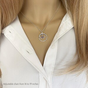 May include: A silver necklace with a double circle pendant and a small purple stone in the center. The chain is adjustable from 16 to 19 inches.