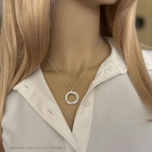 May include: A silver necklace with a multi-ring pendant. The chain is adjustable from 16 to 19 inches.