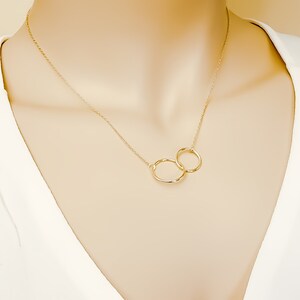 May include: A gold necklace with two interlocking circles as a pendant.