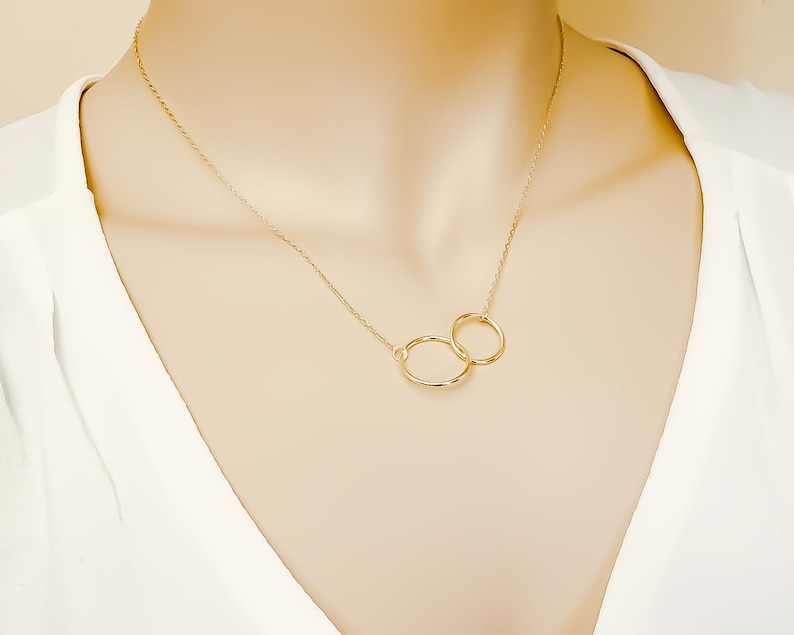 May include: A gold necklace with two interlocking circles as a pendant.
