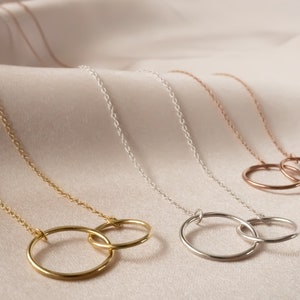 May include: Three gold necklaces with interlocking circle pendants. The necklaces are in gold, silver, and rose gold.