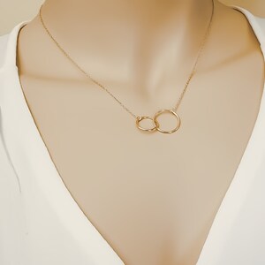 May include: A gold necklace with two interlocking circles as a pendant.
