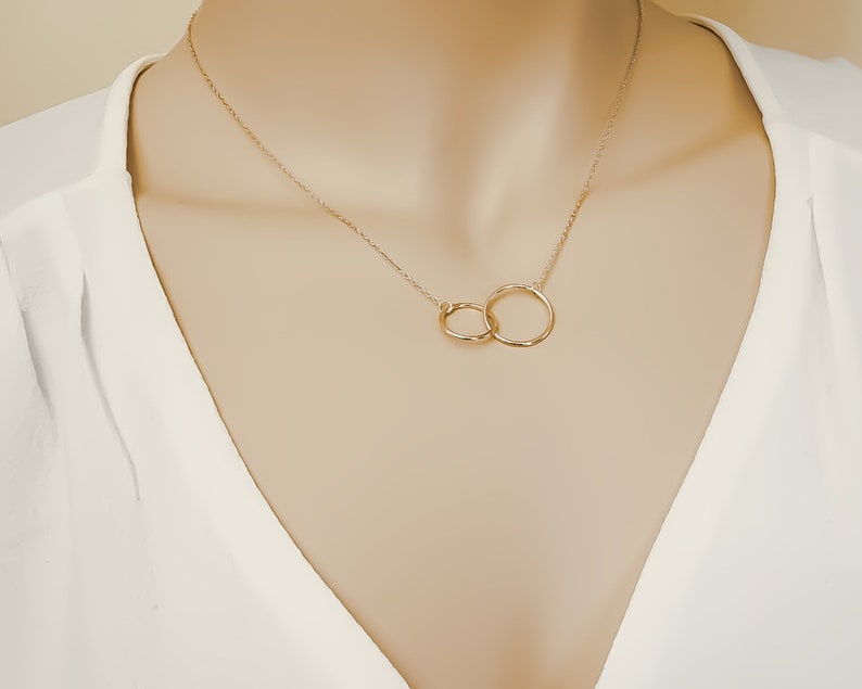 May include: A gold necklace with two interlocking circles as a pendant.