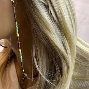 Eyeglass chain on a model. The beaded section is 6 inches on each side with a 15 section of leather that you can barely see. The leather rests on your neck for comfort. 
The beads are small, 8 mm in size.
